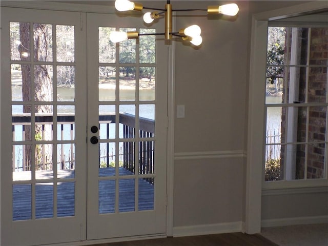 entryway featuring baseboards, a chandelier, and french doors