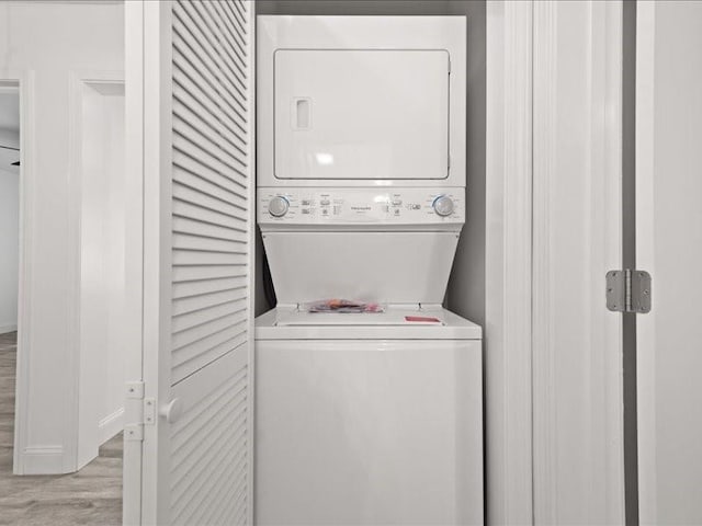 laundry room with light hardwood / wood-style flooring and stacked washing maching and dryer