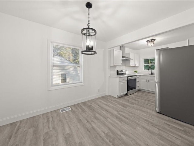 kitchen featuring white cabinetry, wall chimney exhaust hood, appliances with stainless steel finishes, and a wealth of natural light