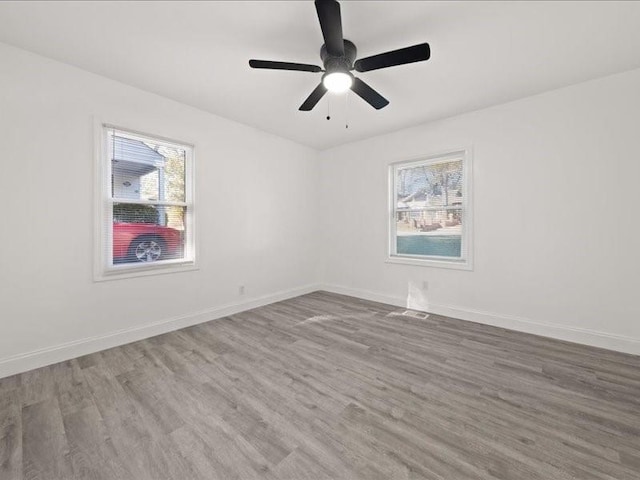 unfurnished room featuring ceiling fan, hardwood / wood-style floors, and a healthy amount of sunlight