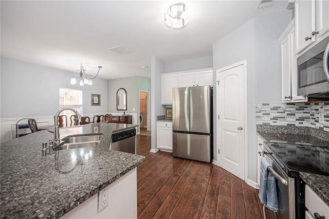 kitchen with dark wood-style floors, a sink, white cabinets, appliances with stainless steel finishes, and a notable chandelier