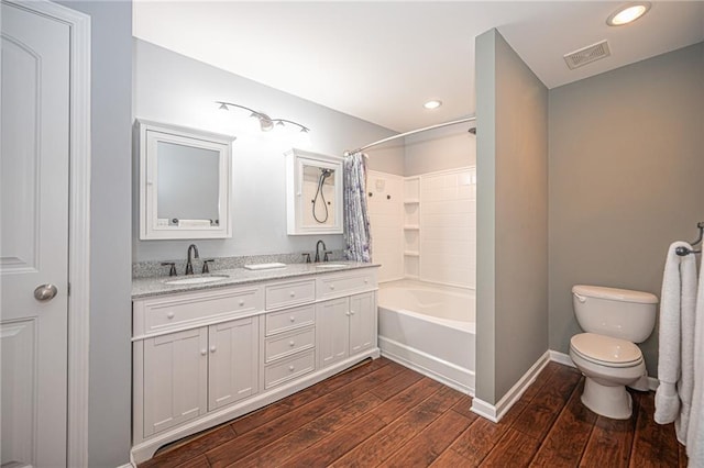 bathroom with toilet, wood finished floors, visible vents, and a sink