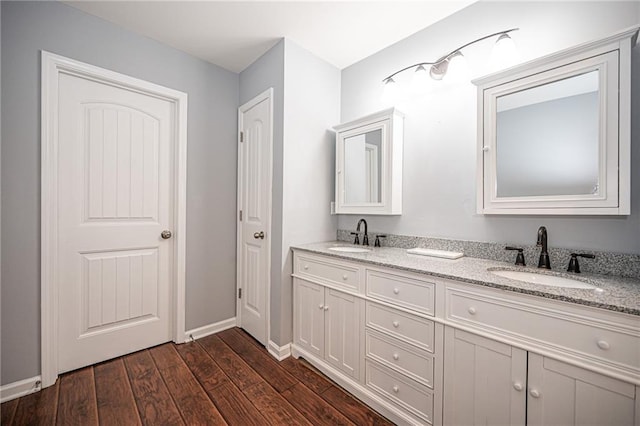 bathroom featuring double vanity, wood finished floors, baseboards, and a sink