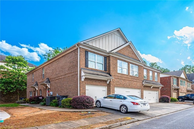 view of property featuring central AC unit, driveway, an attached garage, board and batten siding, and brick siding