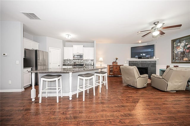 kitchen with visible vents, appliances with stainless steel finishes, a breakfast bar, and dark wood-style flooring