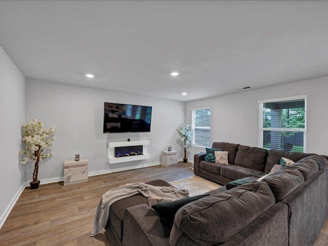 living room featuring light wood finished floors, recessed lighting, baseboards, and a fireplace