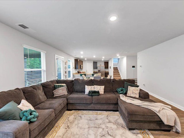 living room featuring stairs, wood finished floors, baseboards, and recessed lighting