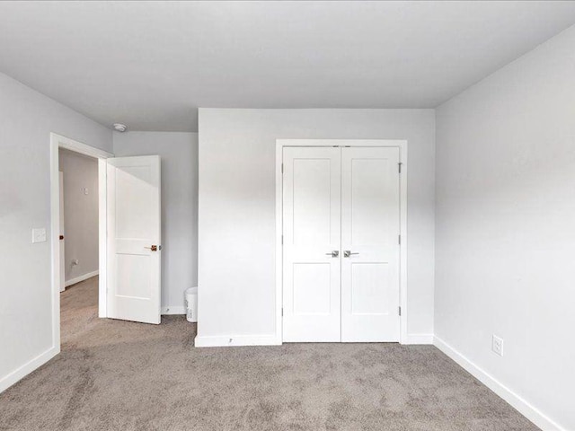 unfurnished bedroom with carpet, baseboards, and a closet
