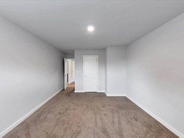 carpeted empty room featuring baseboards