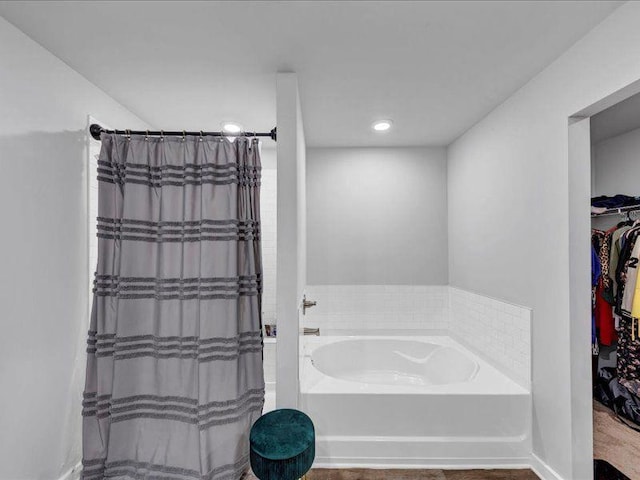 bathroom with a bath, a shower with shower curtain, recessed lighting, and a walk in closet