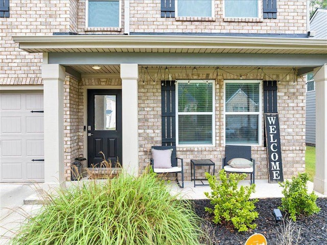 property entrance featuring a porch, brick siding, and a garage