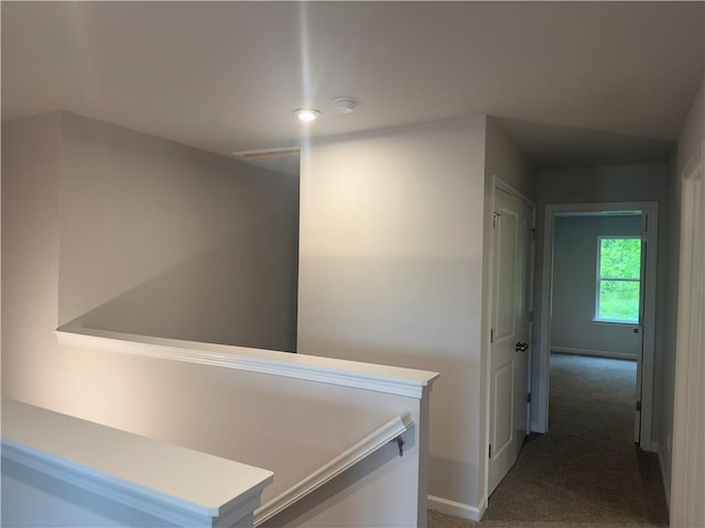 hallway with baseboards, an upstairs landing, and carpet