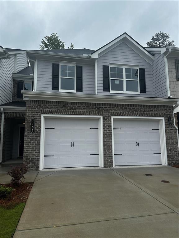 view of front facade with concrete driveway, a garage, and brick siding