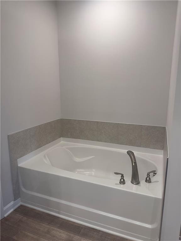 bathroom with a garden tub and wood finished floors