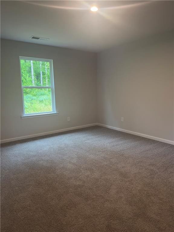 empty room with visible vents, baseboards, and dark colored carpet