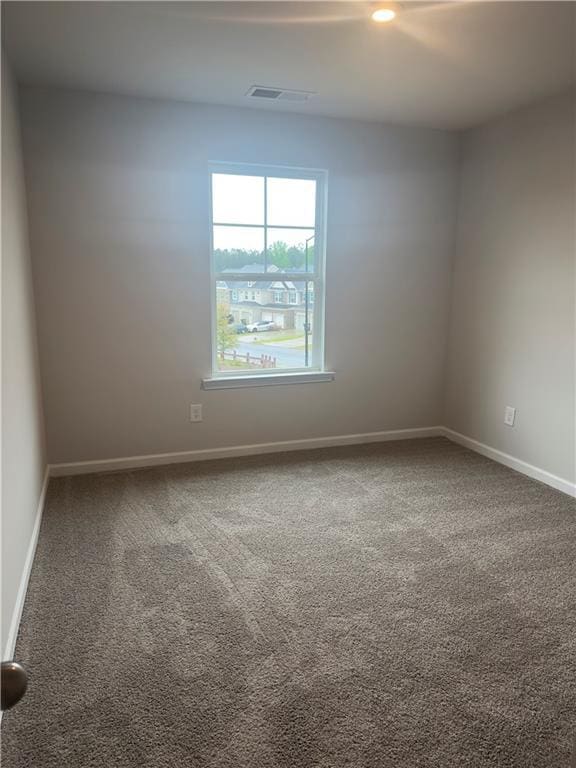 spare room featuring baseboards, visible vents, and carpet floors