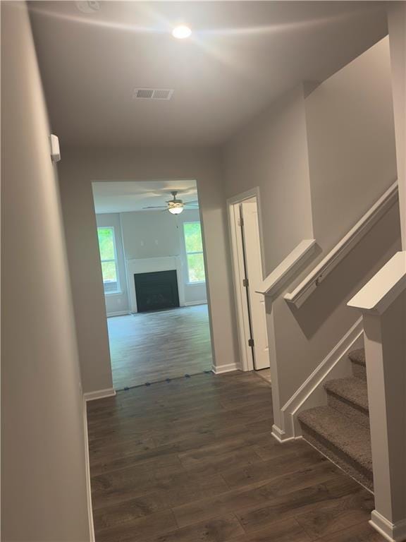 hall featuring baseboards, stairway, visible vents, and dark wood-type flooring