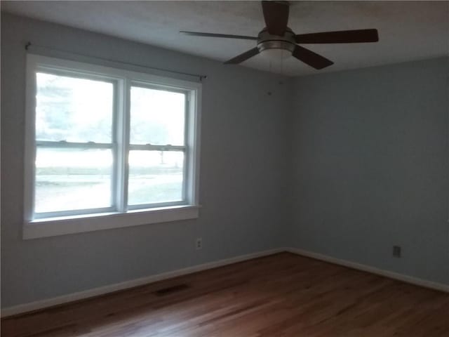 unfurnished room featuring visible vents, ceiling fan, baseboards, and wood finished floors