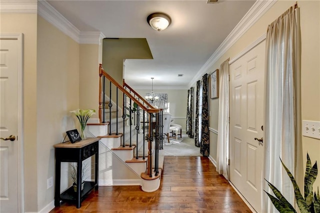 entrance foyer featuring a notable chandelier, ornamental molding, and dark hardwood / wood-style flooring