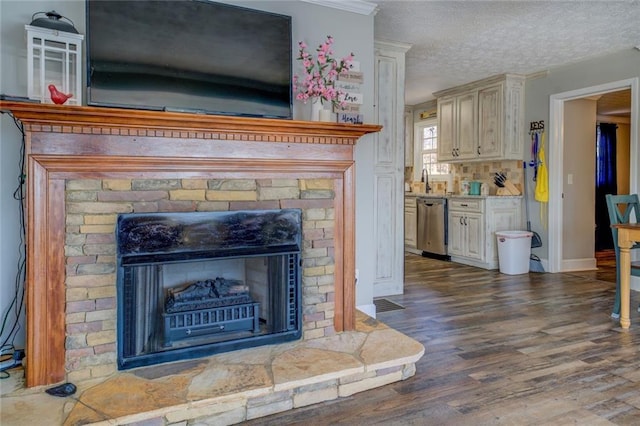 interior details featuring a fireplace, a textured ceiling, wood finished floors, dishwasher, and baseboards