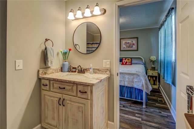 ensuite bathroom featuring baseboards, wood finished floors, connected bathroom, and vanity