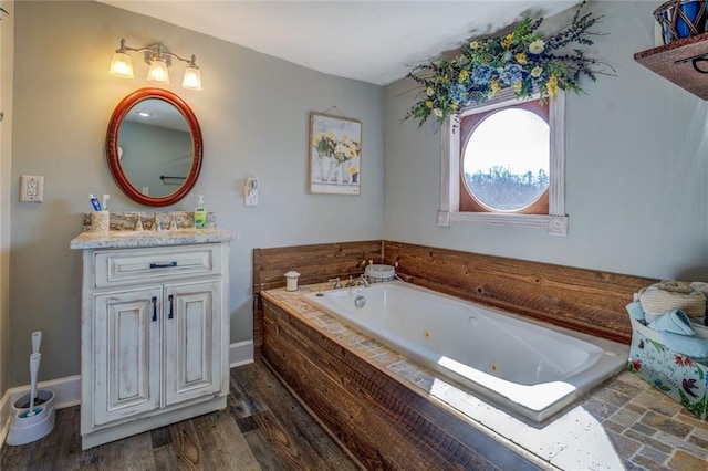 bathroom featuring a whirlpool tub, baseboards, wood finished floors, and vanity