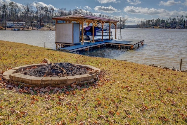 view of dock featuring a fire pit, a lawn, and a water view