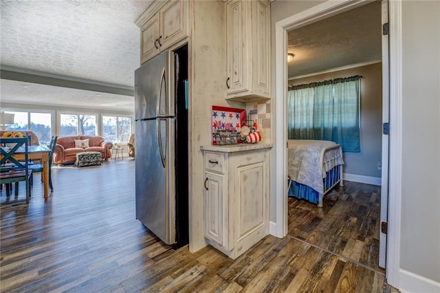 kitchen featuring a textured ceiling, open floor plan, light countertops, freestanding refrigerator, and dark wood-style floors