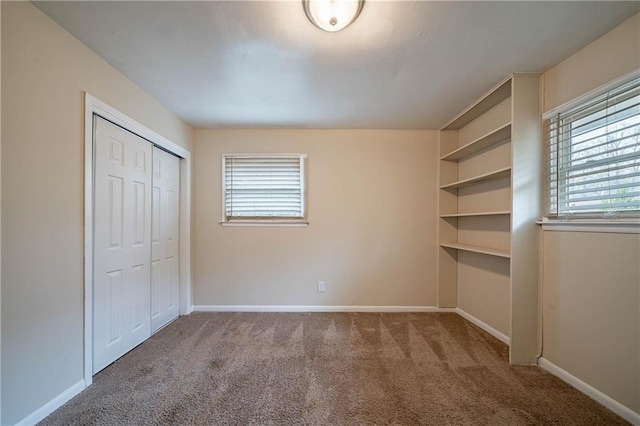 unfurnished bedroom featuring multiple windows, carpet floors, and a closet