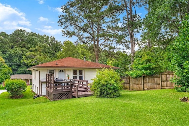 back of property featuring fence, a wooden deck, and a lawn