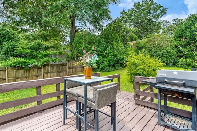 wooden terrace with outdoor dining area, fence, and a lawn