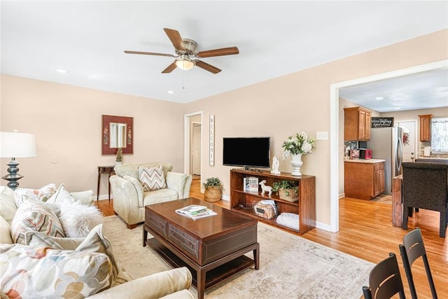 living room featuring a ceiling fan, recessed lighting, baseboards, and light wood finished floors