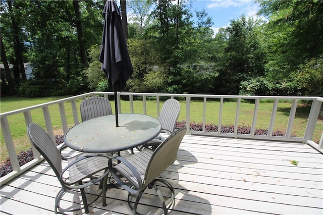 wooden deck featuring a lawn and outdoor dining area