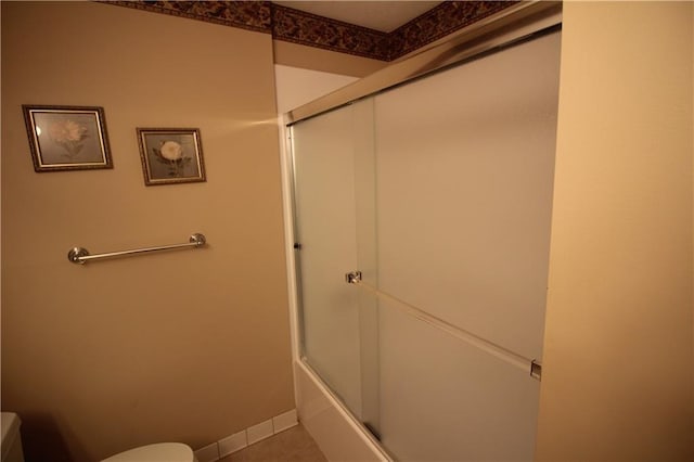 bathroom with tile patterned flooring, toilet, and shower / bath combination with glass door