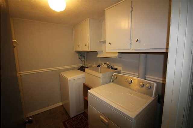 laundry room featuring washer and dryer, a sink, cabinet space, a textured ceiling, and baseboards