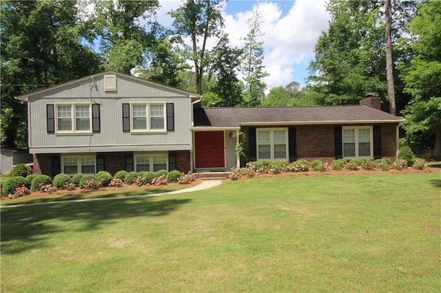tri-level home featuring a front lawn, brick siding, and a chimney