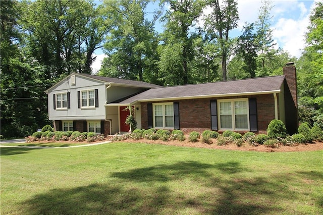 split level home with a chimney, a front yard, and brick siding