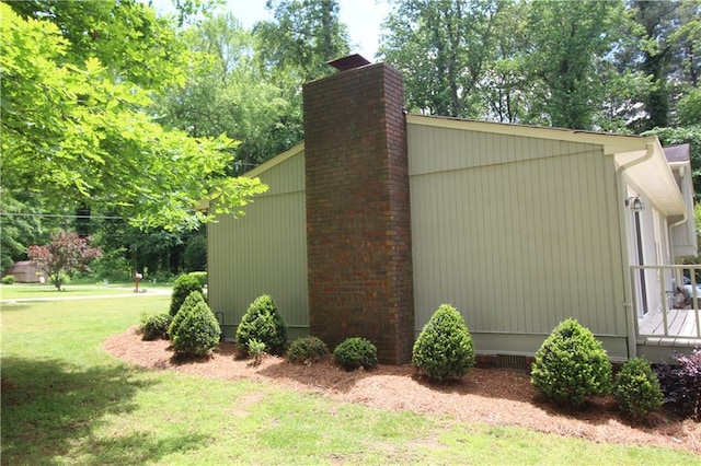 view of home's exterior with a chimney and a lawn