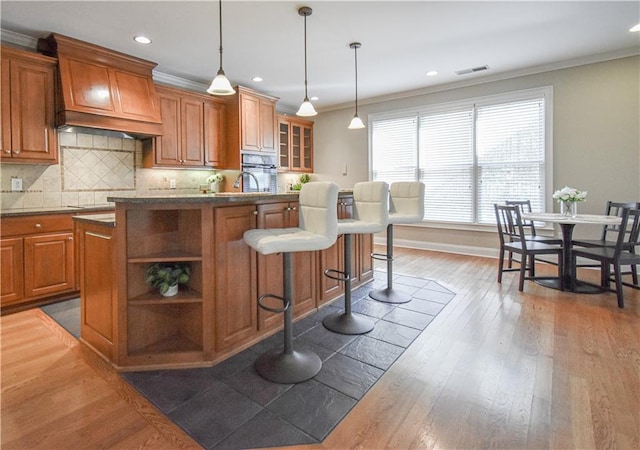 55 Little Barley Ln, Grayson, GA 30017 - kitchen featuring premium range hood, brown cabinets, a center island with sink, crown molding, and dark wood finished floors