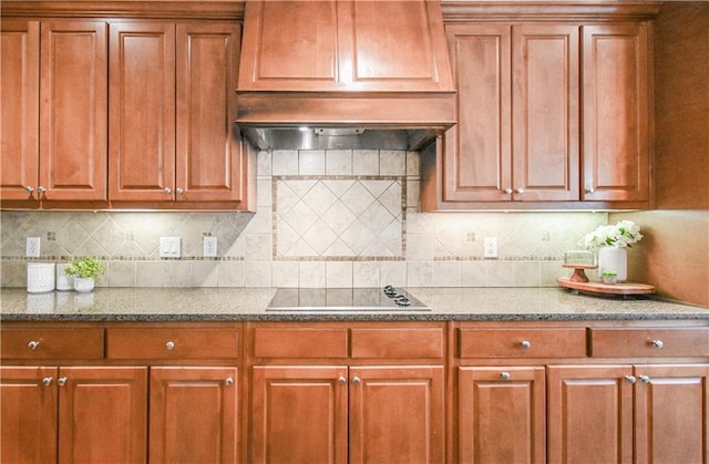 55 Little Barley Ln, Grayson, GA 30017 - kitchen featuring black electric cooktop, dark stone counters, brown cabinets, and decorative backsplash