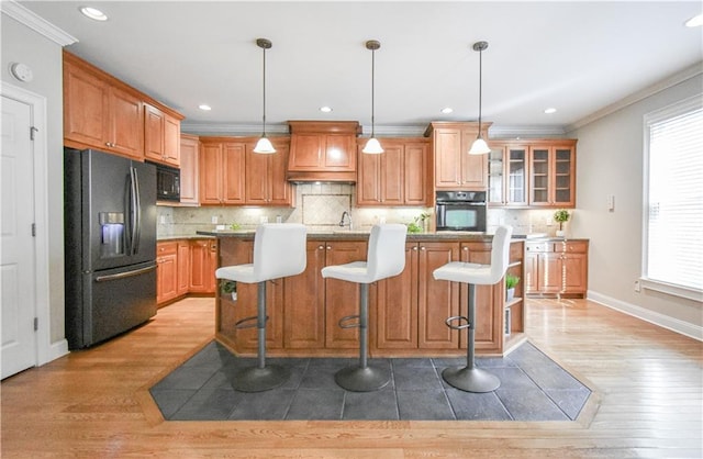 55 Little Barley Ln, Grayson, GA 30017 - kitchen with black appliances, premium range hood, light wood finished floors, ornamental molding, and backsplash