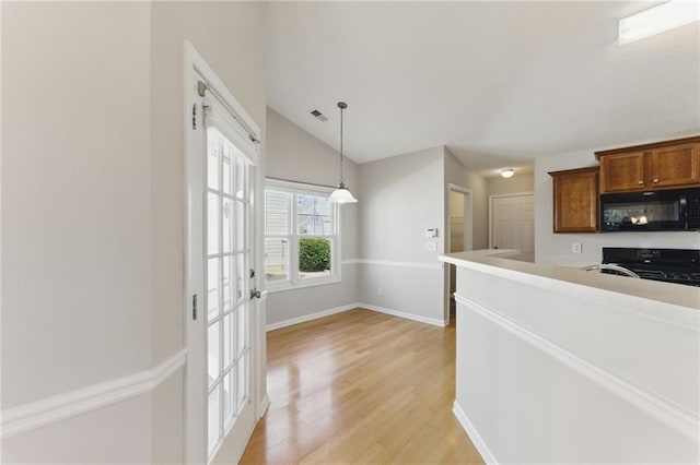 kitchen with visible vents, lofted ceiling, decorative light fixtures, light wood-type flooring, and black appliances