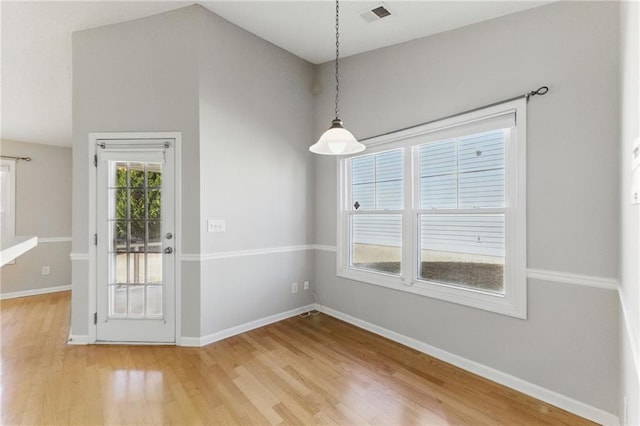 unfurnished dining area featuring visible vents, baseboards, and wood finished floors