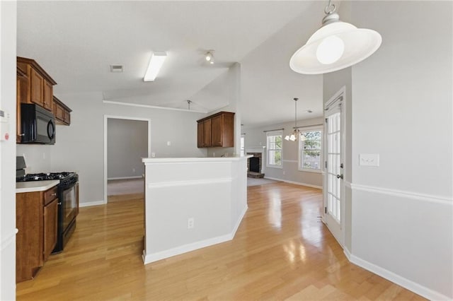 kitchen featuring visible vents, light wood-style floors, vaulted ceiling, black appliances, and decorative light fixtures