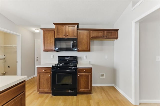 kitchen featuring black appliances, brown cabinets, light countertops, and light wood-style floors