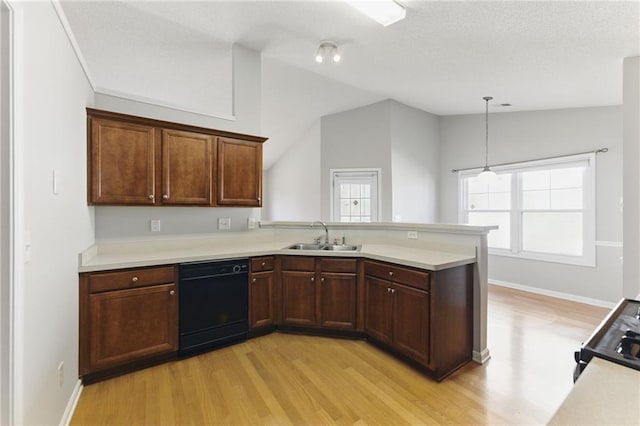 kitchen featuring a peninsula, vaulted ceiling, light countertops, black appliances, and a sink