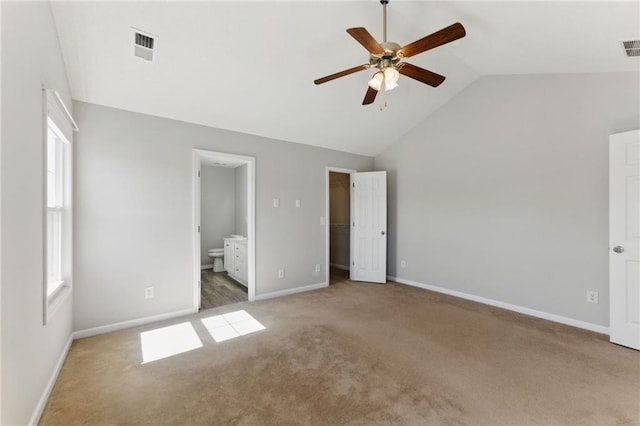 unfurnished bedroom featuring carpet floors, lofted ceiling, visible vents, a spacious closet, and ensuite bathroom