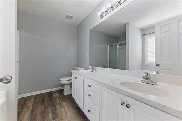 bathroom with visible vents, a sink, a shower stall, and toilet