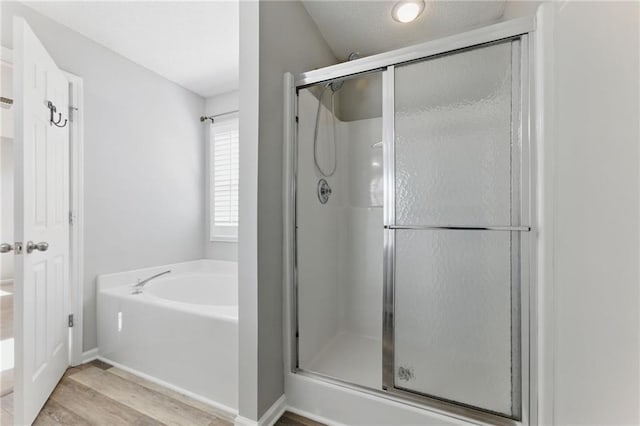 full bathroom with a garden tub, a shower stall, baseboards, and wood finished floors