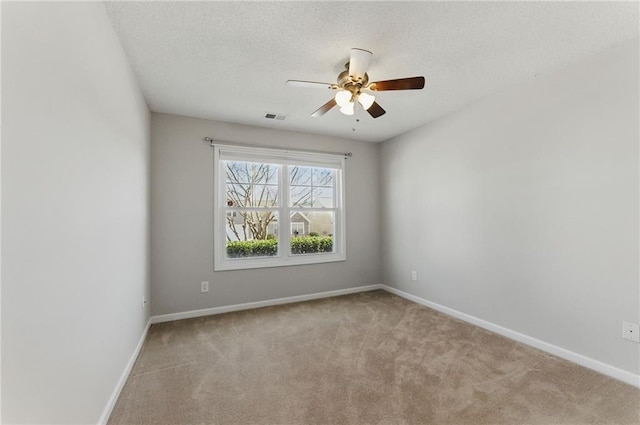 carpeted spare room with baseboards, visible vents, and ceiling fan